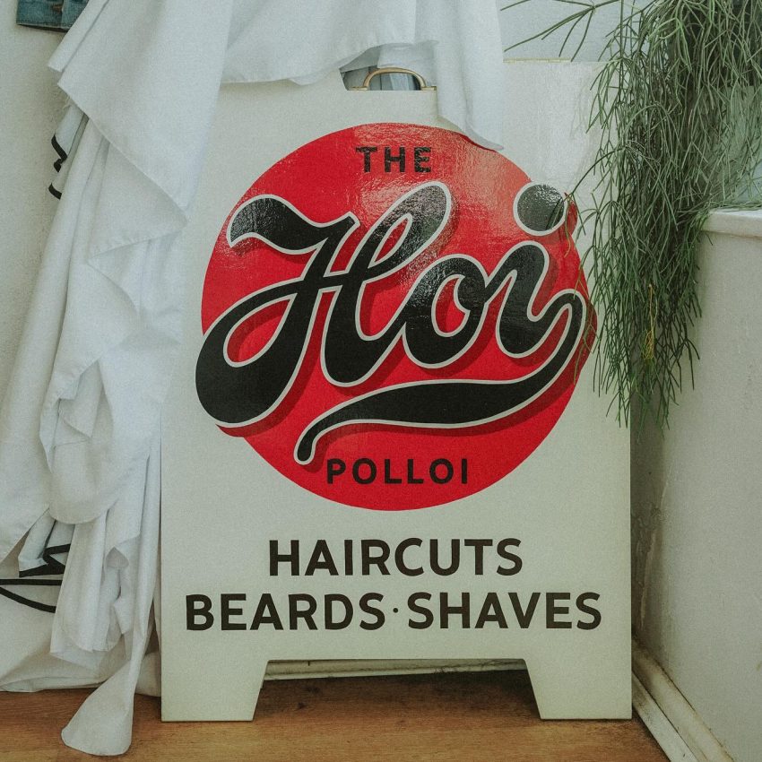 Signboard poster that says The Hoi Polloi, haircuts, beards, shaves.